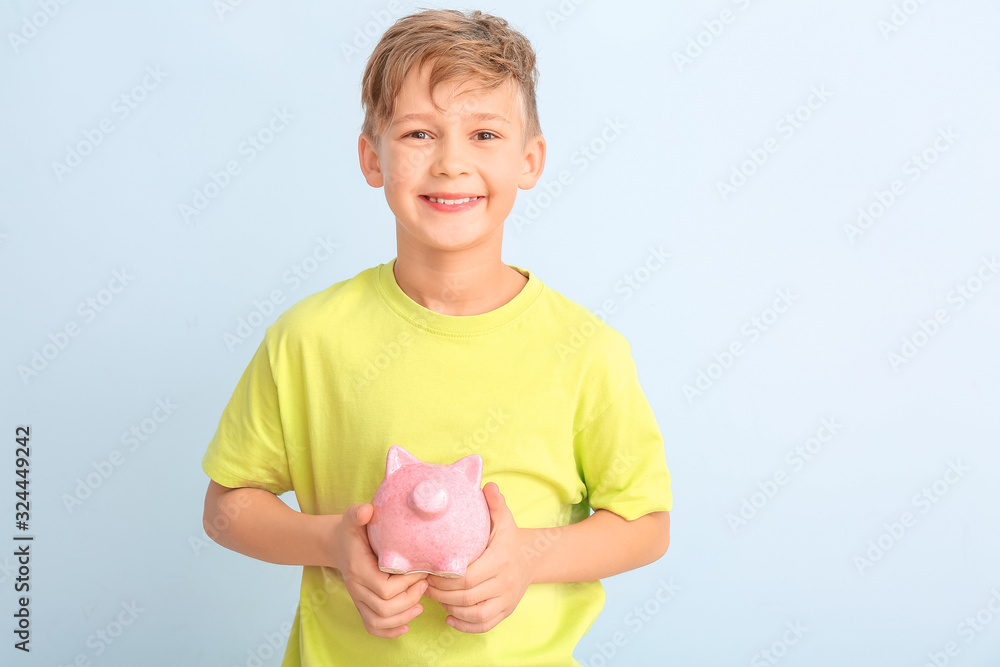 Cute boy with piggy bank on white background