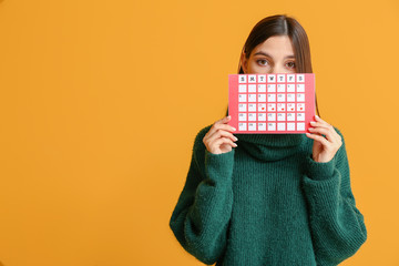 Wall Mural - Young woman with menstrual calendar on color background