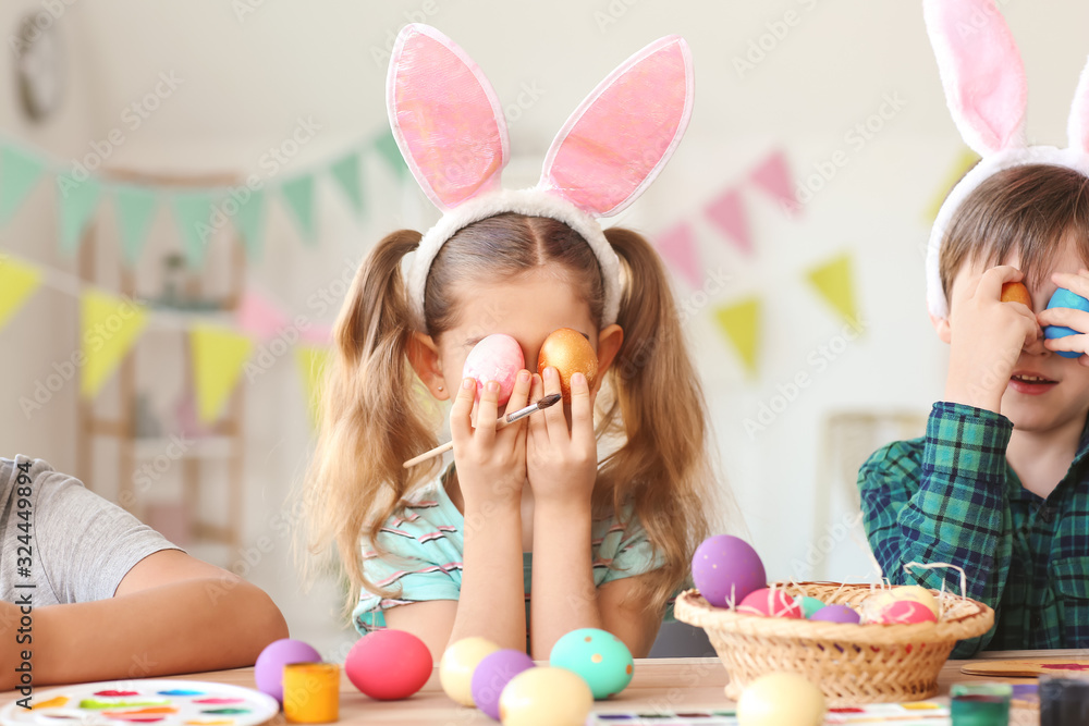 Little children painting Easter eggs at home