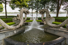 Four Snake Statues On An Active Fountain In A Public Green Park