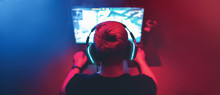 Blurred Background Professional Gamer Playing Tournaments Online Games Computer With Headphones, Red And Blue