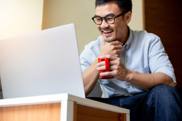 using computer.asian man hand typing message keyboard laptop chatting friend.search information form internet while sitting on sofa.concept for use technology device contact communication business