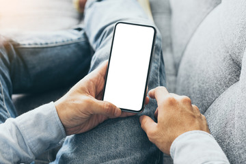 Mockup image blank white screen cell phone.man hand holding texting using mobile on sofa at home.background empty space for advertise text.people contact marketing business,technology