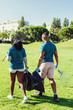 © Mangostar - Volunteers cleaning lawn from litter. Rear view of black woman and Latin man walking through grass and carrying rakes and plastic bags. Garbage collection concept