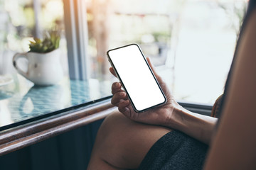 Mockup image blank white screen cell phone.woman hand holding texting using mobile on desk at coffee shop.background empty space for advertise text.people contact marketing business,technology