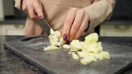 Wall Mural - experienced housewife with nice manicure cuts vegetables cooking dish for lunch at kitchen marble table close-up