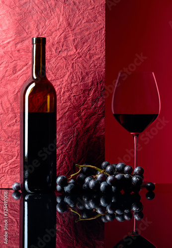 Fotomural Bottle and glass of red wine on a black table.