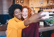 © Sanja - Two women at a cafe taking a selfie together.