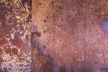 two sheets of rusty metal welded together lie on each other.