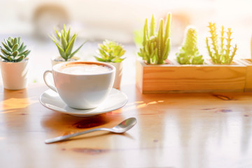 Wall Mural - latte coffee in a classic white coffee cup decoration with cactus green leaf