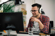 © JustLife - Attractive businessman in office. Young programmer with headphones singing at work.