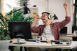 © JustLife - Attractive businessman in office. Young programmer with headphones singing at work.