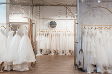 A Lot Of Beautiful White Wedding Dresses On Hangers In The Store
