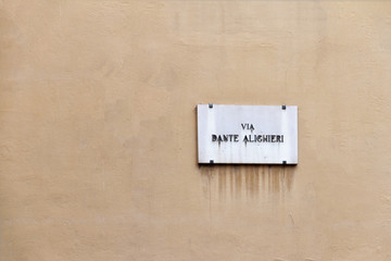 old Dante Alighieri street nameplate on ancient yellow wall in Florence in Italy