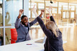 © Carlos David - Portrait of a happy smiling young man in business suit with woman coworker or client celebrating with arms and fists up in office meeting, with contract and pen