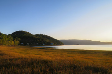 Wall Mural - Beautiful sunrise over a golden field at L'Anse Saint-Jean in the Saguenay Fjord