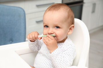 Canvas Print - Cute little baby with spoon in highchair at home