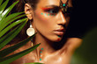 canvas print picture - Closeup portrait of woman tanned skin colored makeup tropical jungle paint on the face sweat plant palm leaves wild style exotic accessory beautiful sexy model ethnic model.