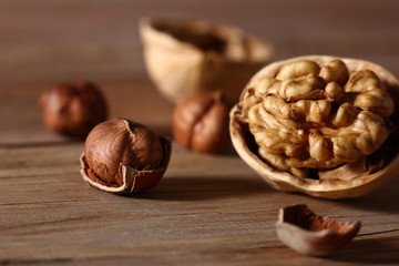 Wall Mural - hazelnuts and walnuts with split shells on a wooden table close-up