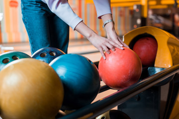  cropped view of young woman choosing bowling ball