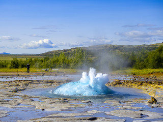 exploding Geyser with a man with a tablet taking a picture in the background