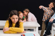 © LIGHTFIELD STUDIOS - selective focus of upset schoolgirl near classmates gossiping while schoolboy pointing with finger isolated on black, bullying concept