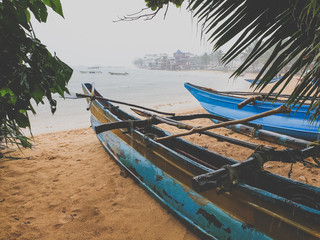 Toned image of heavy tropical rain on the beach. Old wooden fishing boats on the sandy ocean beach.