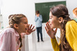 © LIGHTFIELD STUDIOS - selective focus of schoolgirls gossiping near upset classmate, bullying concept