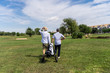 Couple of men in hats walking on a golf course with a cart to carry the equipment