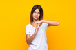 Young woman over isolated yellow background making time out gesture