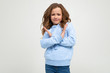© Ivan Traimak - serious teenage girl in casual blue hoodie refuses crossing her arms in front of herself on a white background with copy space