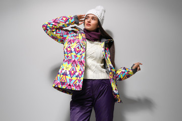 Wall Mural - Woman wearing stylish winter sport clothes on light grey background