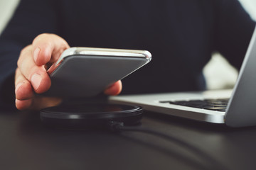 Wall Mural - man puts mobile phone on wireless charger on table