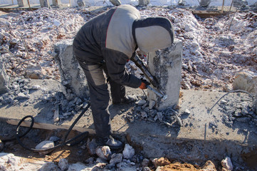 A worker works with a jackhammer at a construction site