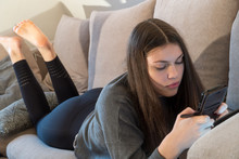 Young Woman Using Her Smartphone At Home On The Couch