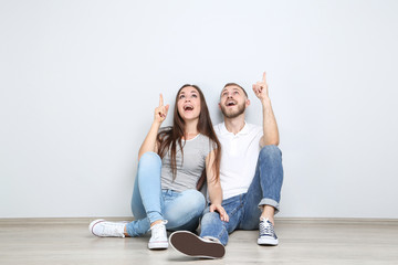 happy young couple sitting on the floor and showing fingers up