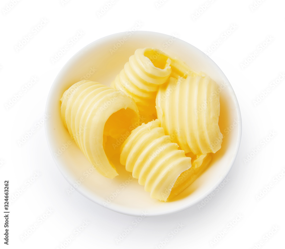 Butter curls or butter rolls in white bowl isolated. Top view. - obrazy, fototapety, plakaty 