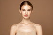 © Beauty Agent Studio - Beautiful young woman with perfect skin standing and looking at camera against beige background. Beauty treatment and spa concept.