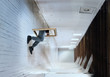 Man climbing through frame into clean white room, conceptual image