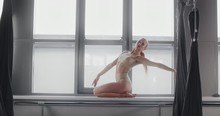 Attractive Young Blonde Woman Makes Acrobatic Gymnastic Tricks In Slow Motion On The Windowsill Of Yoga Studio, Flexible Woman Does Acrobatic And Plastic Exercises, Yoga And Stretching, 4k DCI 60p