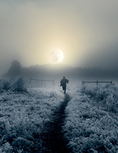 Dramatic Artistic Image Of Man Running Toward Rising Moon In Winter Landscape