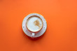 Cappuccino coffee cup on orange background.   Top view with copy space