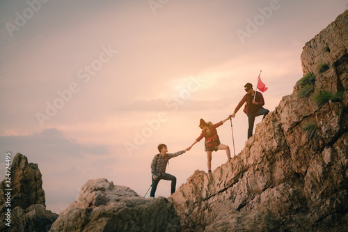 Team of climbers man and woman hiker holding hands to help each other up the hill with red flags for hiking for mountain climbing success. Hiking, hikers, team, mountain, climb, activity concept.