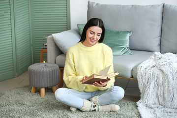 Sticker - Beautiful young woman in warm sweater reading book at home