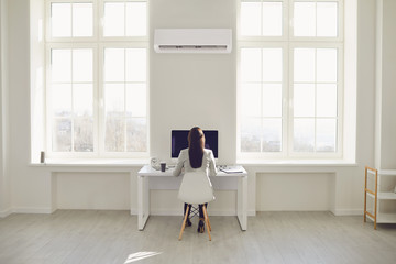 The young man turns on the air conditioner cools the air while sitting on the sofa in the room