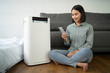 Air purifier , Asian Business woman working with laptop use phone  with filter for clean room in a living room