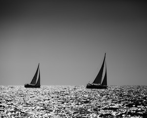 Black and white image of two yachts silhouette in high sea