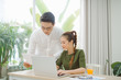 © makistock - Wide shot of smiling couple surfing in laptop sitting at table