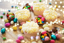 Easter, Food And Holidays Concept - Frosted Cupcakes With Chocolate Eggs And Candies On Table