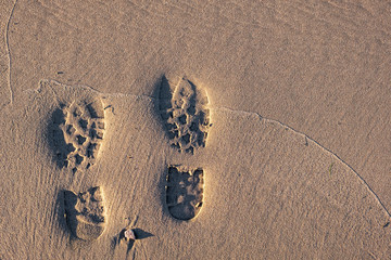 Trekking boots footprints on wet sand. Imprint of rubber boots on sand.